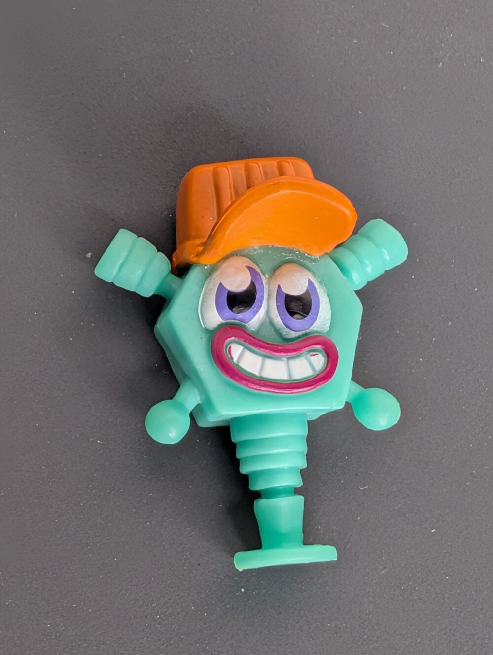 Blue & orange plastic toy with a smiling face and orange cap